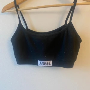 Svart croppad linnetopp och shorts med 'Angel'-tryck - Säljer en svart croppad linnetopp och matchande shorts med 'Angel'-tryck. Perfekt för en avslappnad sommarlook. Toppen har smala axelband och shortsen är bekväma med elastisk midja.