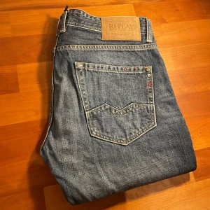 Blå jeans från Replay - Snygga blå jeans från Replay med klassisk femficksdesign och knappgylf. De har en stilren look med diskreta detaljer och en bekväm passform. W30 L34. Modell: ROB.