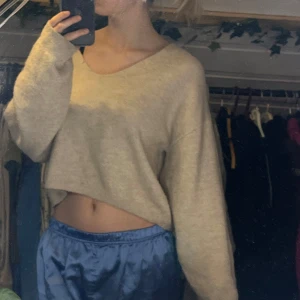 Beige croppad tröja - Säljer en mysig beige croppad tröja med v-ringning. Tröjan har långa ärmar och är perfekt för en avslappnad stil. Passar bra till både jeans och kjol. Inge fel på den alls och har knappt andvänt den. Sticks inte alls! Super mysig.