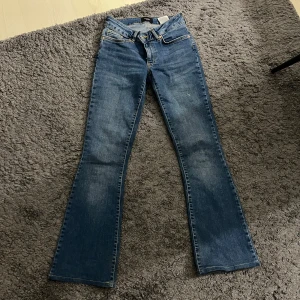 Blå jeans från Vero Moda - Snygga blå jeans från Vero Moda med klassisk femficksdesign och knappgylf. De har en flared stil som ger en trendig look. Säljer dem för att dem är för små. Dem är lågmidjade.