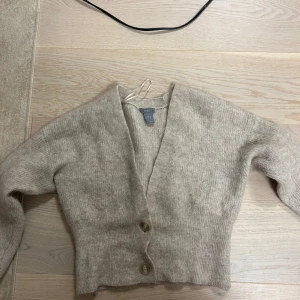 Beige kofta från Lindex - Mysig beige kofta från Lindex i storlek S. Den är stickad och har en v-ringad design med knappar framtill. Alpaca & ull 