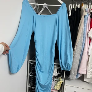 Ljusblå klänning från Shein - Säljer en superfin ljusblå klänning från Shein. Den har långa ärmar och en snygg rynkad detalj längs sidan som ger en cool effekt. Även på baksidan finns en rynkad detalj längst ryggen. Klänningen är perfekt för fest och materialet känns mjukt. 