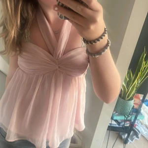 Rosa halterneck topp från Nelly - Säljer en superfin rosa halterneck topp från Nelly i storlek 34. Toppen har en knytning i nacken. Den är gjord av ett lätt och luftigt material, perfekt för sommaren. Toppen är i nyskick och har en lös passform.