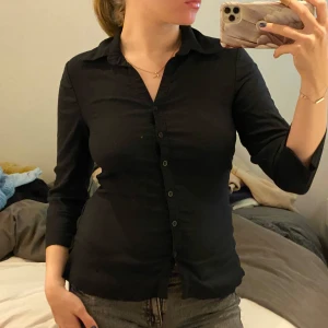 Svart skjorta med knappar - Säljer en stilren svart skjorta med knappar framtill. Den har en klassisk krage och långa ärmar, perfekt för både vardag och fest. Skjortan är i bra skick och passar till många olika outfits. 🖤