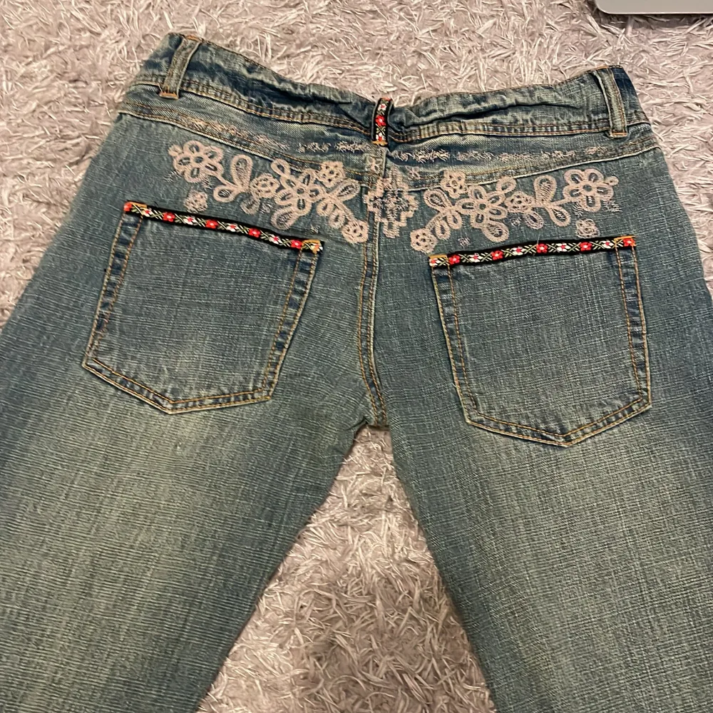 Vintage bootcut/straight midwaist jeans med blomdetaljer både fram och bak Innerbenslängd: 79 cm Midejemått: 38.5 cm tvärs över Priset kan diskuteras  Skriv för fler bilder. Jeans & Byxor.