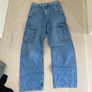 Baggy blå cargo jeans - Baggy blå jeans med 2 större fickor på låren och 4 vanliga fram och bak. Highwaist. Köpte för 350