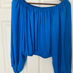 Blå offshoulder topp från Bik Bok - Säljer en superfin blå offshoulder topp från Bik Bok i storlek S. Den har långa ärmar och en lös passform, perfekt för sommardagar eller en kväll ute. Toppen är gjord i ett lätt och luftigt material som känns skönt mot huden. Passar både till jeans och kjol! 💙