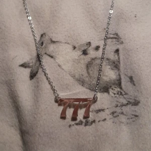 Halsband med änglanummer - Ett silvrigt halsband med änglanummret 777 (lycka, välstånd, tur).