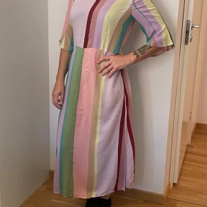 Färgglad randig klänning från Soulmate - Säljer en superfin långklänning från Soulmate med färgglada ränder i rosa, grön, gul och vinröd. Klänningen har trekvartsärmar och en bekväm passform. Perfekt för vår och sommar! 🌸