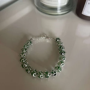 Grönt och silverfärgat armband - Snyggt armband med gröna och silverfärgade detaljer. Perfekt för att ge en touch av färg till din outfit. Armbandet har en elegant design med små gröna pärlor inramade av silverfärgade länkar. Passar både till vardags och festliga tillfällen.