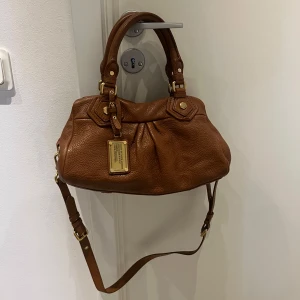 Marc Jacobs väska  - Mått 31,5 x 19 cm📏Väskan är i mini storleken. Jätte fint vintage väska, äkta läder som skadar sig inte av regn/vatten. Perfekt färgen nu till hösten, väskan är felfritt🩷 fraktas spårbar och möter även upp i centrala Stockholm 📍