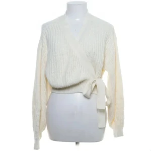 Vit omlottkofta - Säljer en stilren vit omlottkofta med knytband i midjan. Koftan är stickad och har långa ärmar. Gräddvit