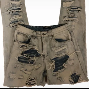 Jaded London ‘Extreme Ripped’ jeans - Säljer ett par beige jeans med en riktigt sliten look. De har flera stora revor och slitningar över hela byxorna, vilket ger en edgy stil. Perfekta för dig som vill ha en avslappnad och trendig look.