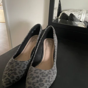 Grå leopardmönstrade klackskor  - Snygga grå klackskor med leopardmönster. Perfekta för en trendig look och bekväma att bära hela dagen. 