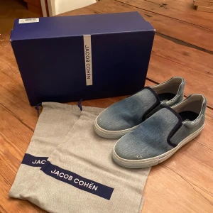 Jacob Cohën skor - Snygga sneakers från Jacob Cohën. Perfekta till sommaren nu! Skicket är 10/10 helt nya. Box och dustbag följer med! Pris i butik: 6000kr+. Sitter större i storleken så skulle passa 40-41! Finns det några funderingar så skriv till mig!  