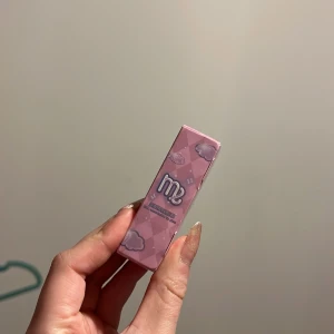 Rosa lippgloss med glitter med molndesign - Sött rosa läppstift med en charmig molndesign på förpackningen. Perfekt för en lekfull look. Helt ny, oöppnad
