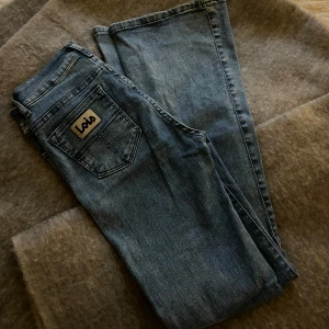 Blå jeans från Lois - Säljer ett par klassiska blå jeans från Lois. De har en bootcut passform och är i designen raval. Jeansen har en traditionell femficksdesign och en knappgylf. Perfekta för en avslappnad stil. Köpta för 1500kr
