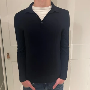 Mörkblå pikétröja - Långärmad piké från H&M i mörkblå färg. Tröjan har inga defekter och är gjord av merinoull. Size (S) modellen är 177cm. Hör av dig vid funderingar!