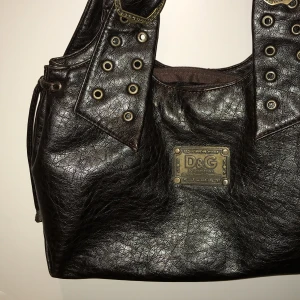 Brun axelväska  - Snygg brun axelväska med metallspännen och nitar. Väskan har dubbla handtag, två fack med dragkedjor på insidan och en stor dragkedja för stora facket. Superfin till utekvällar, men också till vardags!! - Möts upp i Stockholmsområdet 