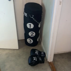 Svarta boxningshandskar från Hammer - Säljer ett par svarta boxningshandskar från Hammer. Perfekta för träning med en boxningssäck. Handskarna har en stilren design med vit logotyp och kardborreband för enkel justering. Den kostar 2500kr men jag valde sänka priset för 1600 eftersom att min son använder inte den. Den passar även bra som julklapp present eller en födelsdag present❤️