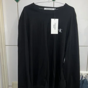 Svart långärmad tröja från Calvin Klein Jeans - SPRILLANS NY!! Snygg svart långärmad tröja från Calvin Klein Jeans med det ikoniska CK-logotypen tryckt på bröstet och ryggen. Perfekt för en stilren och avslappnad look.