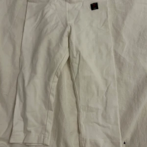 Vita byxor från Polarn O. Pyret - Säljer ett par vita byxor från Polarn O. Pyret i storlek 104. Byxorna är tillverkade av ekologiskt material och har en enkel design med resår i midjan för bekväm passform. De kommer tvättas och strykas innan de skickas! ⭐️