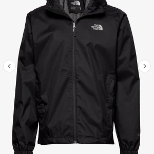 Svart vindjacka från The North Face - Snygg och praktisk svart vindjacka från The North Face med dragkedja och huva. Perfekt för blåsiga dagar. Jackan har elastiska muddar vid ärmsluten för extra komfort.
