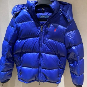 Blå Shine/glänsig Vinterjacka Från Polo Ralph Lauren - Säljer en Sällsynt sjukt fet vinterjacka då jag inte behöver den längre. Skick 9-10/10. Köpt i höstas och använd sparsamt. Perfekt för vintern och tidig vår. Då den är svår att få tag på vet jag inte nypriset men Ca: 7000.