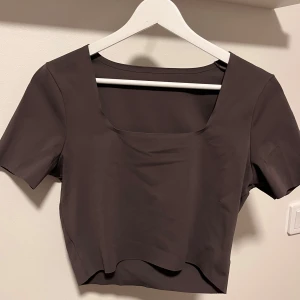 Mörklila kortärmad topp från ICANIWILL - Snygg mörklila topp från ICANIWILL med korta ärmar och fyrkantig halsringning. Perfekt för en stilren look på gymmet! Mycket skönt och stretchigt material.