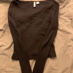 Svart topp💕👀 - Ribbad långärmad topp💕 Passar till allt med fin omlottdetalj vid ringningen.  Strl S men sitter som en XS😇 Nyskick!!