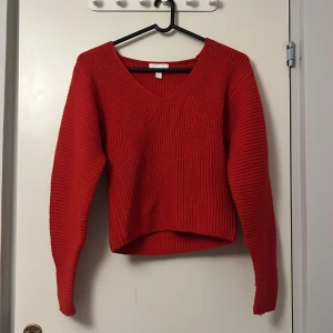 Röd stickad tröja från H&M - Säljer en snygg röd stickad tröja från H&M. Tröjan har en v-ringad design och långa ärmar, perfekt för kyligare dagar. Den är i en härlig röd färg som verkligen poppar. Passar perfekt till både jeans och kjol! Använd 1-2 gånger.