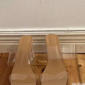 Transparenta klackskor med beige sula - Snygga klackskor med transparenta remmar och klack. Skorna har en beige sula som ger en stilren look. Perfekta för att ge en modern touch till din outfit.