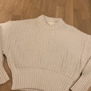 Vit stickad tröja från H&M - Mysig vit stickad tröja från H&M med ribbad krage och muddar. Perfekt för kyliga dagar med sin tjocka och varma design. Tröjan har en klassisk look som passar till många olika stilar.