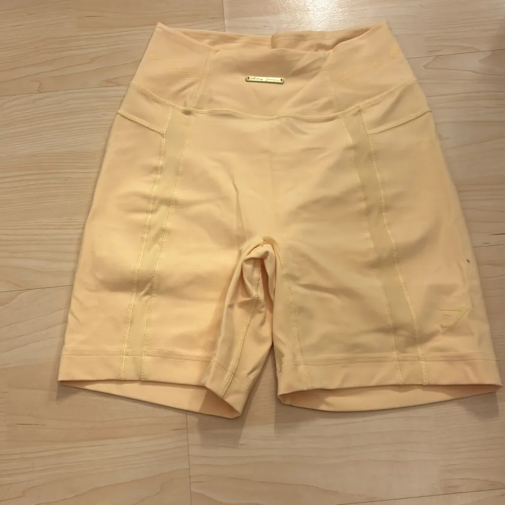 Snygga beige shorts från Victoria's Secret med hög midja. Perfekta för en avslappnad dag eller träning. De är gjorda i ett mjukt och stretchigt material som ger en bekväm passform. Matchande topp är utlagd, som sagt färgen tas inte riktigt upp i kameran, mer gul i verkligheten. Lappen bortklippt men storlek XS. Shortsit.