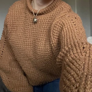 Brun stickad tröja från Zara - Mysig brun stickad tröja från Zara med en hög krage och långa ärmar. Perfekt för kyliga dagar. Tröjan har en grovstickad struktur som ger en trendig look. Passar bra till jeans eller kjol för en avslappnad stil.