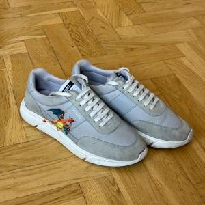 Axel Arigato Genesis runner Pokémon  - Ett par sjukt läckra limited edition skor från Axel arigato med Pokémon tema! Skorna är i storlek 44,5 och i ganska bra skick (se bilder och avgör själv) skulle må bra av en tvätt. Innesulan mäter: 28,5cm 