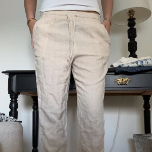 Beige linnebyxor - Snygga och bekväma beige linnebyxor med elastisk midja och dragsko. Byxorna har en loose passform och är bra i längd på mig som är 175cm lång😍