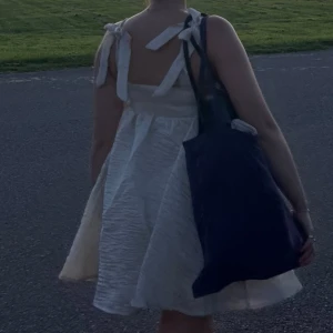 Lojsan Wallin Studentklänning med knytband - Charmig champagnefärgad klänning med knytband på axlarna. Den har en luftig och lätt design med en kort längd som passar perfekt för varma dagar. Materialet ger en elegant textur och klänningen har en söt och feminin stil. Slutsåld och ovanlig🤍 Använd två gånger