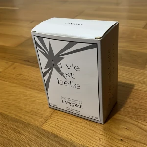 La Vie Est Belle Limited Edition från Lancôme (test) - Upptäck La Vie Est Belle Limited Edition från Lancôme. Denna parfym kommer i en elegant glasflaska med en stjärndesign och en klar kork. Förpackningen är stilren i vitt och silver. Flaskan rymmer 50 ml av denna ikoniska doft. Aldrig använd!