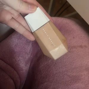 Fenty Beauty Eaze Drop Blurring Skin Tint - Säljer en Fenty Beauty Eaze Drop Blurring Skin Tint i nyans 12. Denna foundation ger en lätt och naturlig täckning med en mjuk finish. Perfekt för en jämn och fräsch look. Innehåller 32 ml.