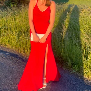 Röd långklänning med öppen rygg - Säljer en superfin röd långklänning med en elegant slits och öppen rygg som passar perfekt till balen. Klänningen har smala axelband som korsas i ryggen och ger en snygg detalj ❣️Den är från JJ’s house och jag är 174 cm lång som prefferens. Säljer för 1200kr men pris kan absolut diskuteras! Hör av er vid frågor! 