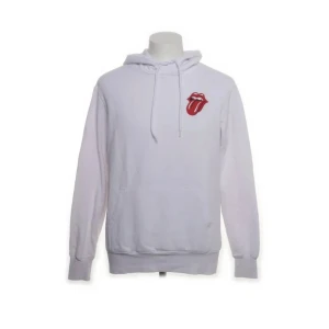 Vit hoodie med Rolling Stones-tryck från Divided - Säljer en vit hoodie från Divided med det ikoniska Rolling Stones-trycket på bröstet och ryggen. Hoodien har en känguruficka och justerbar huva med snören. Perfekt för fans av klassisk rock!