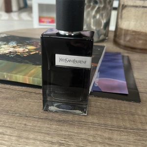 Yves Saint Laurent parfym - Elegant parfymflaska från Yves Saint Laurent i en stilren, mörk design. Flaskan har en fyrkantig form med en svart kork och en tydlig logotyp på framsidan. Perfekt för den som söker en sofistikerad doftupplevelse. Nypris 1200 , mitt pris 650