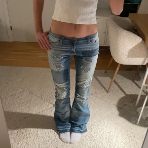 Lågmidjade ljusa jeans med slitningar - Snygga lågmidjade ljusa utsvängda jeans med slitningar och jättecoola detaljer🥰