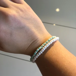 Tvåfärgat pärlarmband - Snyggt armband med små pärlor i vitt och ljusblått. Perfekt för att ge en färgklick till din outfit. Armbandet är elastiskt och passar de flesta handleder.