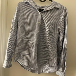 Blåvit randig skjorta från Gina Tricot - Snygg blåvit randig skjorta från Gina Tricot i storlek 36. Skjortan har långa ärmar och knappar framtill. Perfekt för en stilren look.