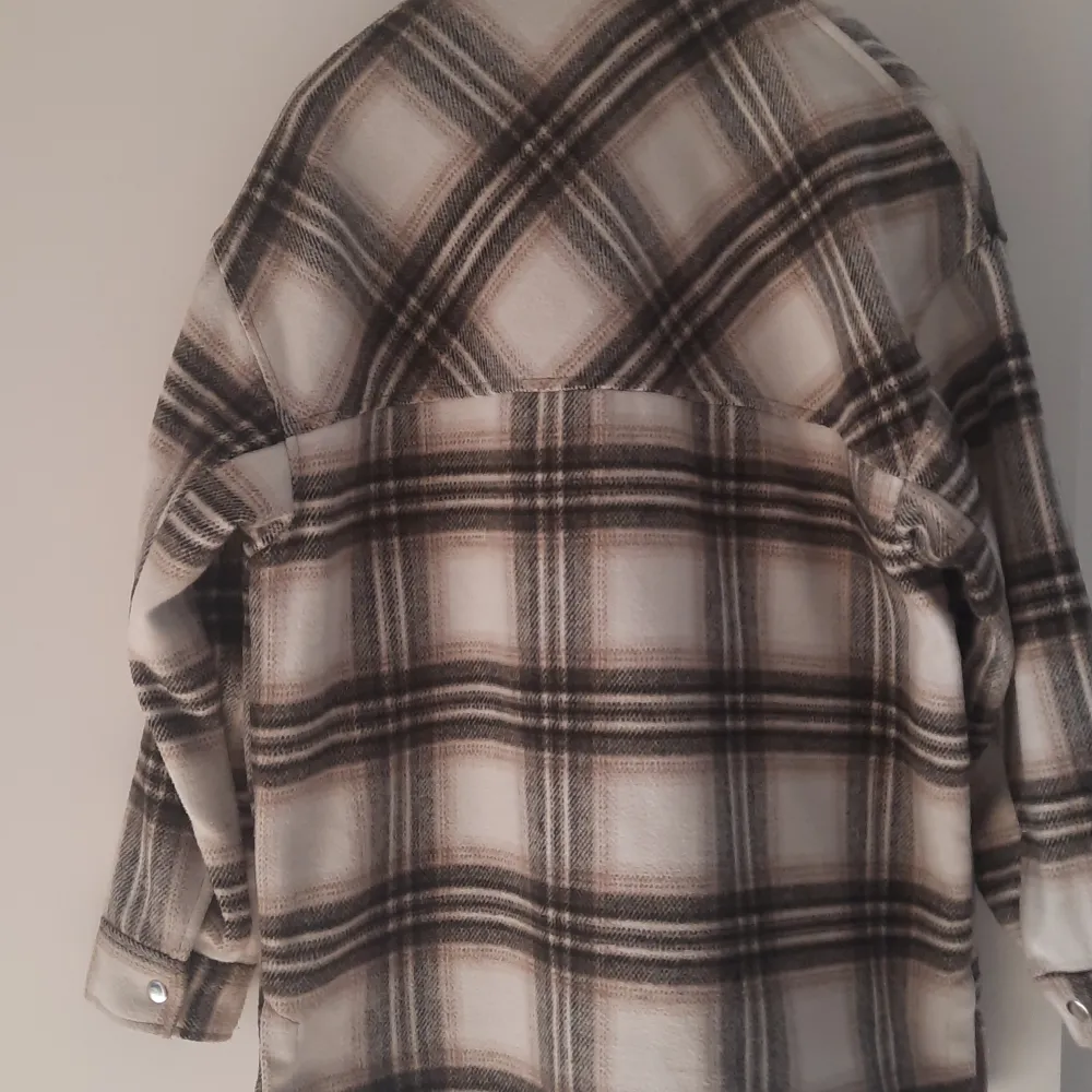 Säljer en snygg rutig overshirt i beige och svart med knappar framtill. Jackan har långa ärmar och två stora bröstfickor. Perfekt för våren som är påväg.. Takit.