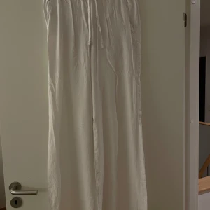 Vita linnebyxor  - Aldrig använts. Vita linnebyxor, mycket mjuka. Breda ben. Skönt och luftigt material                   Midja: 80 cm (men du kan göra den mindre med banden)   bredd nedtill: 25,5 cm  Innersömslängd: 76,6 cm   Ytterlängd (från midjan och ner): 105 cm