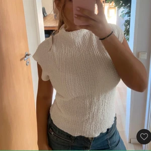 Vit topp från Zara - Säljer en vit topp från Zara i storlek S. Toppen är ärmlös och har en texturerad yta som ger den en unik look. Perfekt för sommardagar eller som ett lager under en jacka.