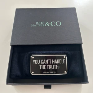 John Hatter mössa mörkblå  - Snygg och stilren mössa från John Hatter & Co. med texten ”You Can't Handle The Truth” på en metallplatta.   Mössan är i fint begagnat skick. Finns vissa märken på metallplattan.   Mössan säljes i originalförpackning.  Nypris 995kr